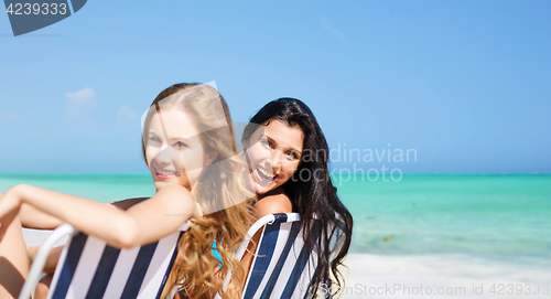 Image of happy women sunbathing on chairs over summer beach