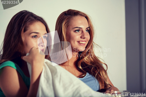 Image of happy friends with popcorn and watching tv at home