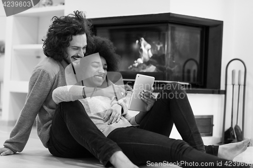 Image of multiethnic couple used tablet computer on the floor