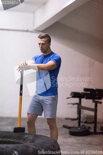 Image of man workout with hammer and tractor tire