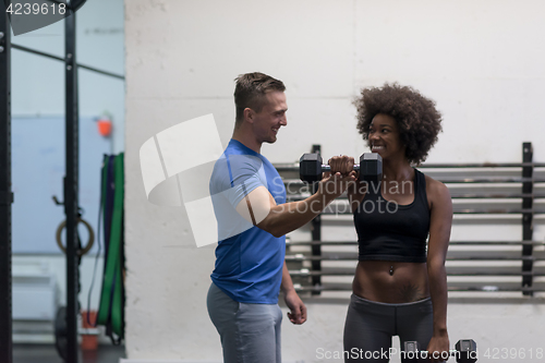 Image of black woman doing bicep curls with fitness trainer