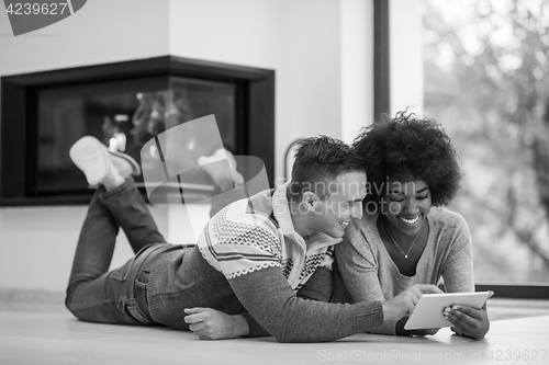 Image of multiethnic couple used tablet computer on the floor