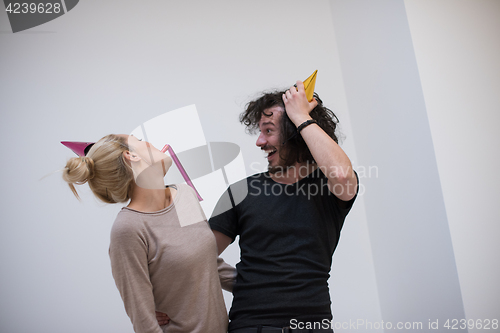 Image of couple in party hats blowing in whistle