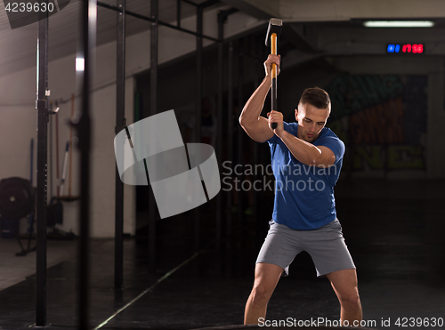 Image of man workout with hammer and tractor tire