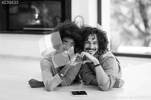 Image of multiethnic couple used tablet computer on the floor