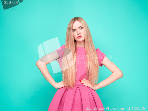 Image of The beautiful young woman in pink mini dress posing at studio