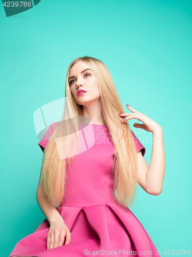 Image of The beautiful young woman in pink mini dress posing at studio