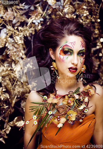 Image of beauty woman with face art and jewelry from flowers orchids clos