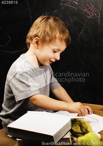 Image of little cute boy with young teacher in classroom studying at blac