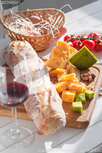 Image of Wine, baguette and cheese on wooden background