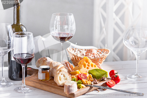 Image of Wine, baguette and cheese on wooden background