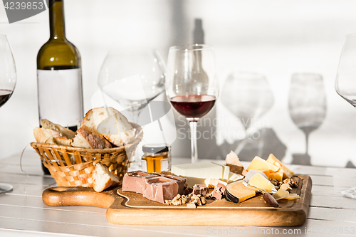 Image of Wine, baguette and cheese on wooden background