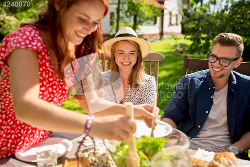 Image of happy friends having dinner at summer garden party