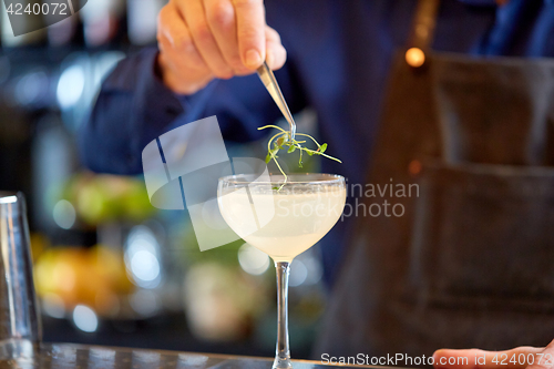 Image of bartender decorating glass of cocktail at bar