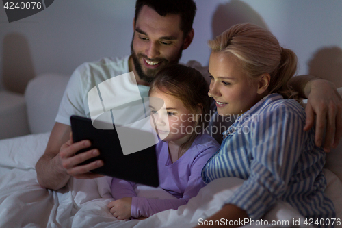 Image of happy family with tablet pc in bed at home