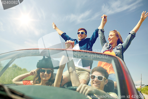 Image of happy friends driving in cabriolet car at country