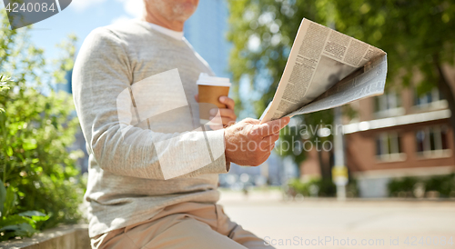 Image of senior man with coffee reading newspaper outdoors