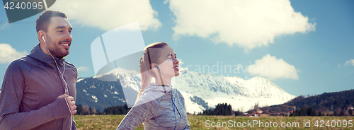 Image of happy couple with earphones running in city