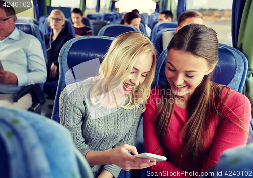 Image of happy young women in travel bus with smartphone