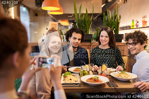 Image of friends with smartphone fotographing at restaurant