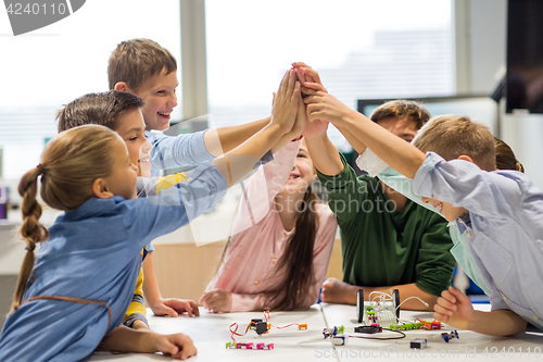 Image of happy children making high five at robotics school