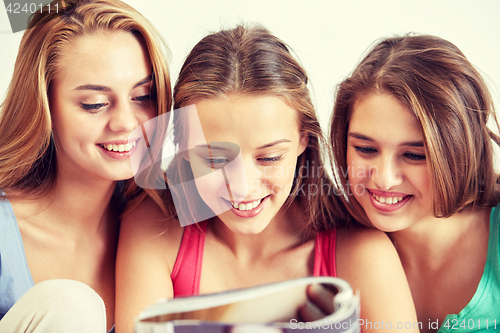 Image of friends or teen girls reading magazine at home