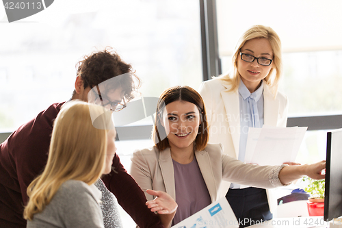 Image of happy creative team with computer in office