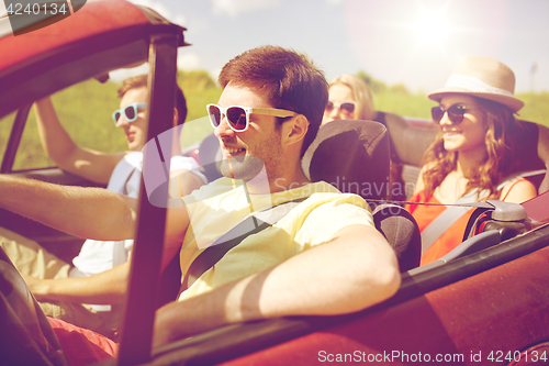 Image of happy friends driving in cabriolet car