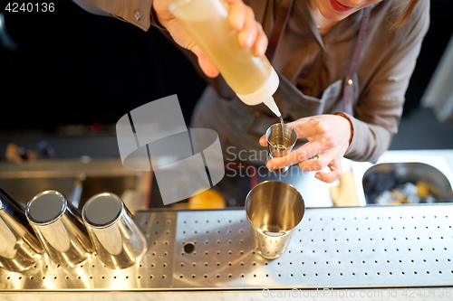 Image of bartender with cocktail shaker and jigger at bar