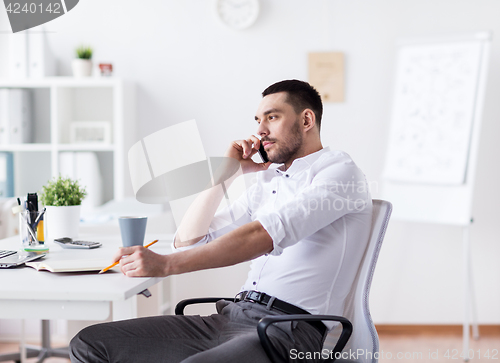 Image of businessman calling on smartphone at office