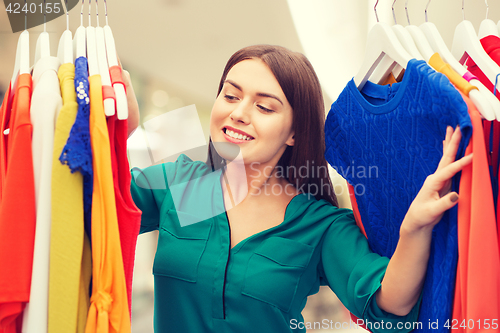 Image of happy woman choosing clothes at home wardrobe