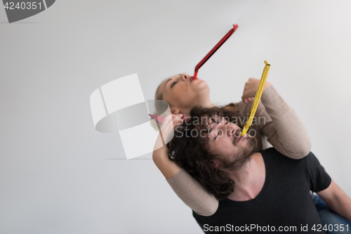 Image of couple in party hats blowing in whistle