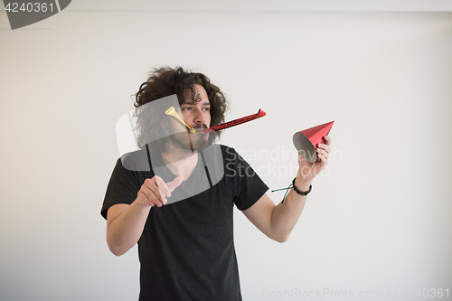 Image of Portrait of a man in party hat blowing in whistle