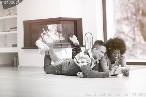 Image of multiethnic couple used tablet computer on the floor