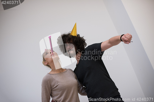 Image of couple in party hats blowing in whistle