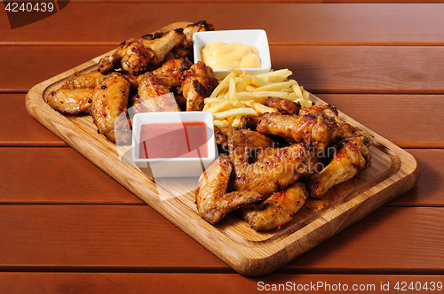 Image of Big wooden board with grilled chicken winds