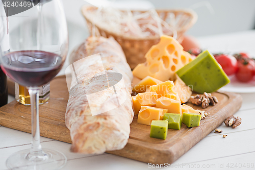 Image of Wine, baguette and cheese on wooden background