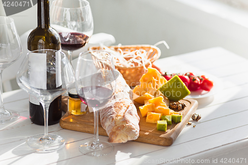 Image of Wine, baguette and cheese on wooden background