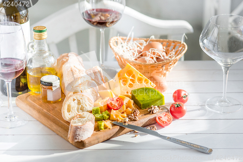 Image of Wine, baguette and cheese on wooden background