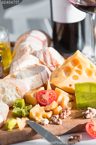 Image of Wine, baguette and cheese on wooden background