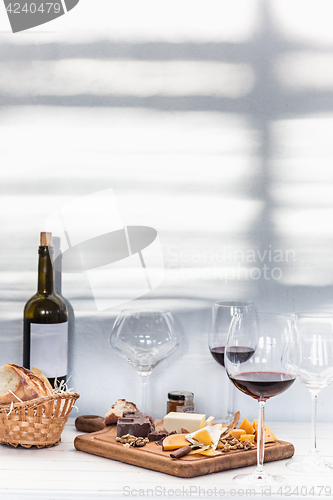 Image of Wine, baguette and cheese on wooden background