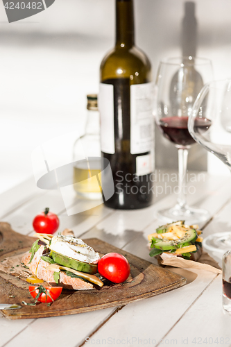 Image of Wine, baguette and cheese on wooden background