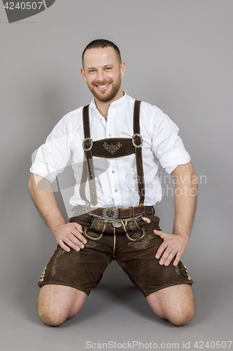 Image of man in bavarian traditional lederhosen kneeling