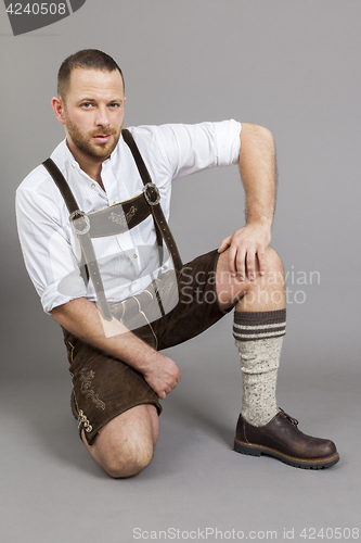 Image of man in bavarian traditional lederhosen kneeling