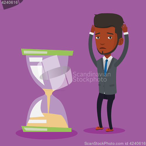 Image of Desperate businessman looking at hourglass.