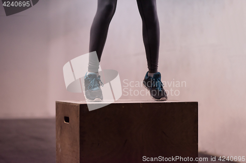 Image of black woman is performing box jumps at gym