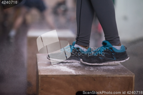 Image of black woman is performing box jumps at gym