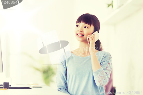 Image of businesswoman calling on smartphone at office