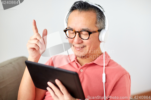 Image of man with tablet pc and headphones at home