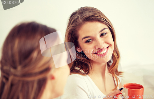 Image of happy young women drinking tea with sweets at home